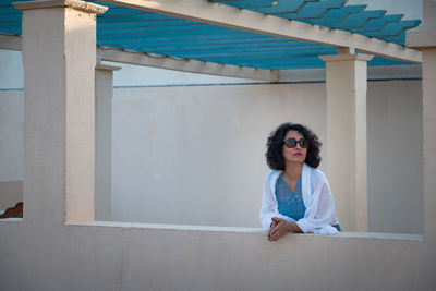 Portrait of woman sitting against wall