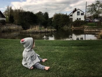 Rear view of boy sitting on grass against trees