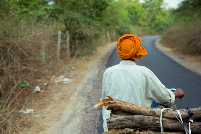 Rear view of man on country road along trees