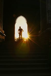 Low angle view of silhouette woman standing on illuminated statue at sunset