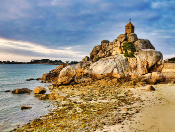 Rock formations on beach against sky