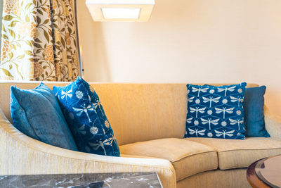 Close-up of illuminated lamp over sofa at hotel room