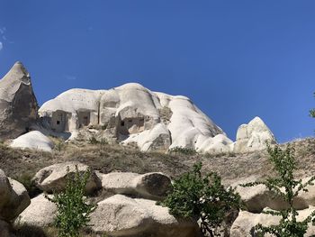 Low angle view of rocky mountains against clear blue sky