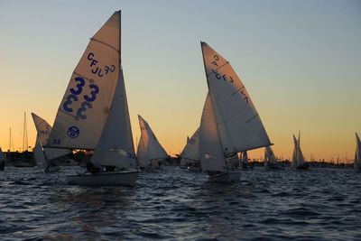 Boats sailing in sea at sunset