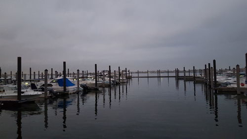 Wooden posts in sea against cloudy sky