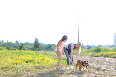 Woman with dog on field against sky