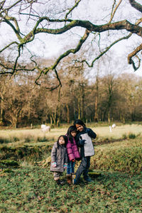 Rear view of people with arms outstretched against trees