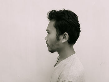 Portrait of young man looking away against white background