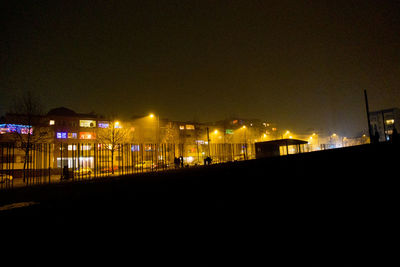 Illuminated cityscape against sky at night