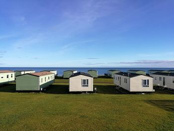 Buildings on field against blue sky