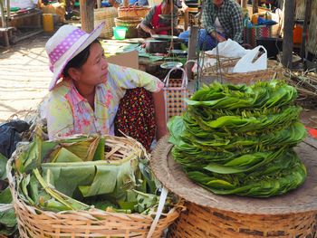 Woman in basket for sale at market stall