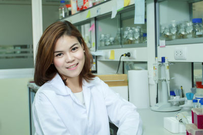 Portrait of smiling young scientist sitting at laboratory