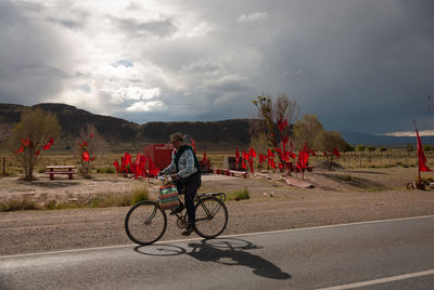 Man riding bicycle on road against sky