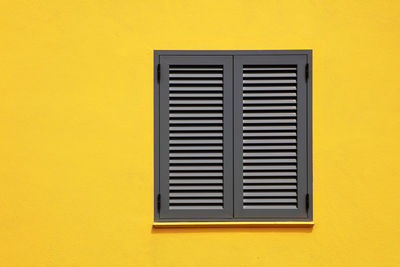 Close-up of window on yellow wall