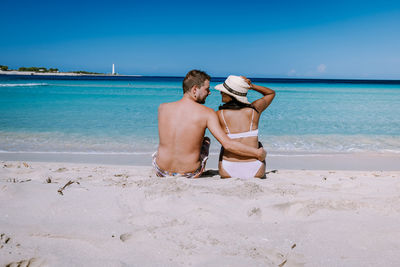 Friends on shore at beach against sky