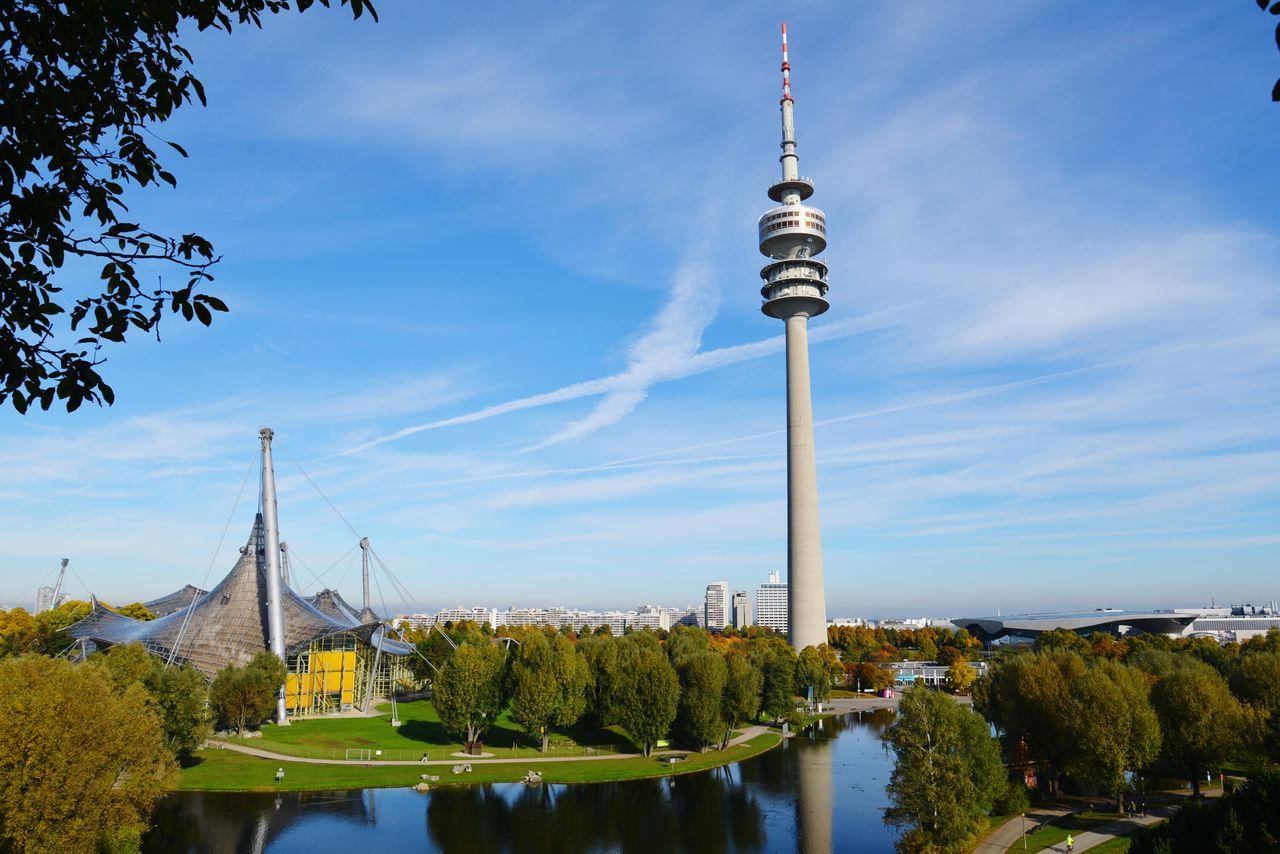 built structure, architecture, tower, sky, communications tower, tall - high, spire, tree, travel destinations, cloud - sky, famous place, city, international landmark, tourism, capital cities, blue, cloud, culture, outdoors, no people, day, tall, cloudy, growth, nature, modern