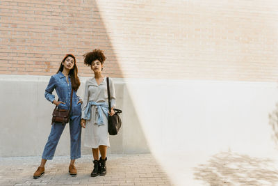 Women with bag standing against brick wall