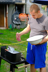 Half-length view of a caucasian young man putting a steak on the grill outside in poland