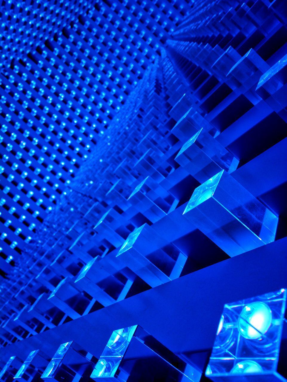 LOW ANGLE VIEW OF ILLUMINATED MODERN BUILDING AT NIGHT