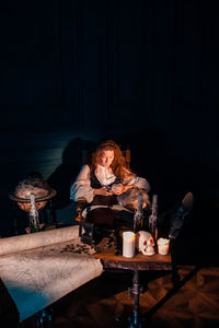 Young woman sitting at table at night