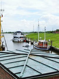 Boats moored at harbor against sky