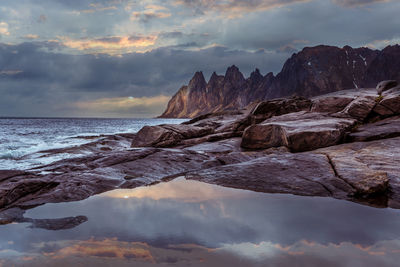 Rocks by sea against sky during sunset