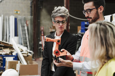 Engineers discussing over robotic arm at industry