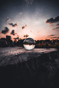 Close-up of crystal ball on water against sky during sunset