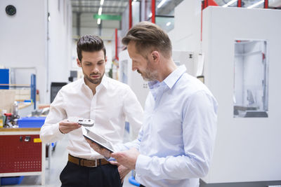 Two men with tablet and product in factory shop floor