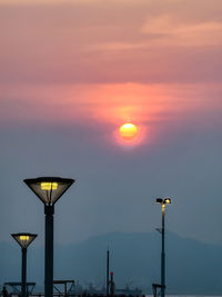 Street lights against orange sky