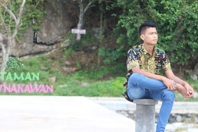 Young woman looking away while sitting on plants