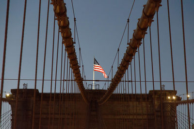 American flag on suspension bridge against clear sky