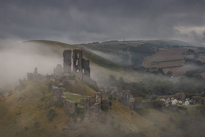 Castle on mountain against sky corfe castle surrounded by mist 