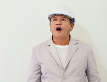 Shocked engineer standing against white wall