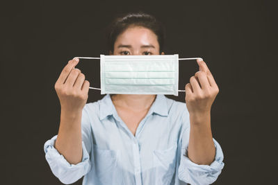 Portrait of man holding paper against black background