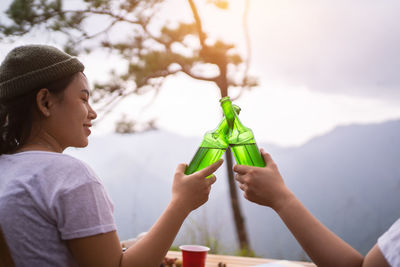 Camping concept, cheers glass bottle by camping people together at their camping site