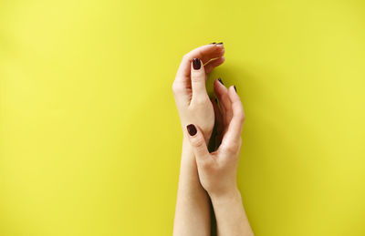 Cropped hands of woman over colored background