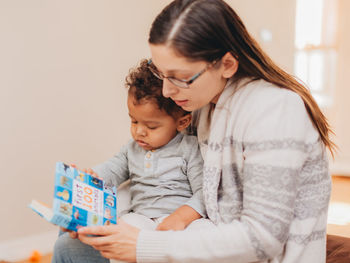 Mother and son reading book at home