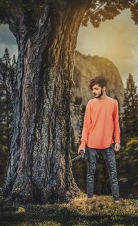 Full length of teenage boy standing on tree trunk