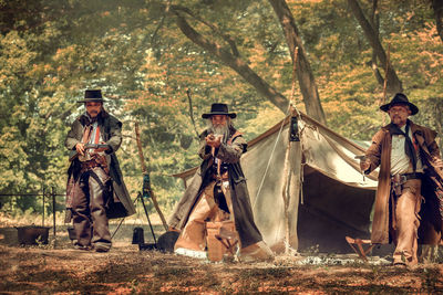 Men aiming guns in forest