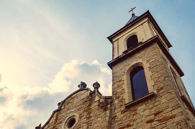 Bottom view of the catholic church against a cloudy sky. cloudy landscape with a stone church.