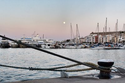 Boats moored in harbor at sunset