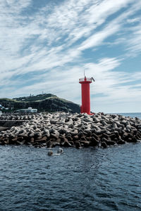 Lighthouse by sea against sky