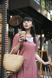 Young woman holding food while looking away outdoors