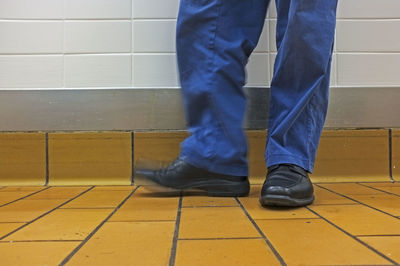 Low section of man standing on tiled floor