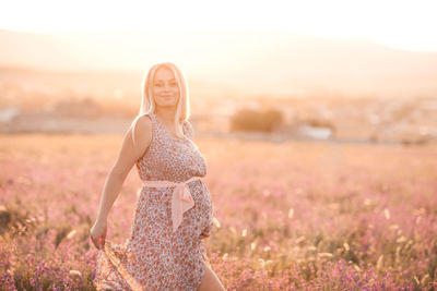 Smiling pregnant woman standing on field