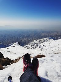 Low section of person on snowcapped mountain against sky