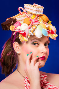 Portrait of woman eating waffle against blue background