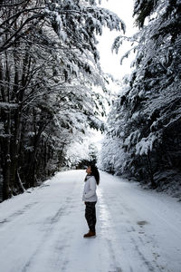 Rear view of person walking on snow covered road