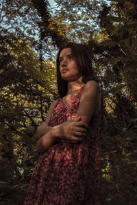 Beautiful woman looking away against trees